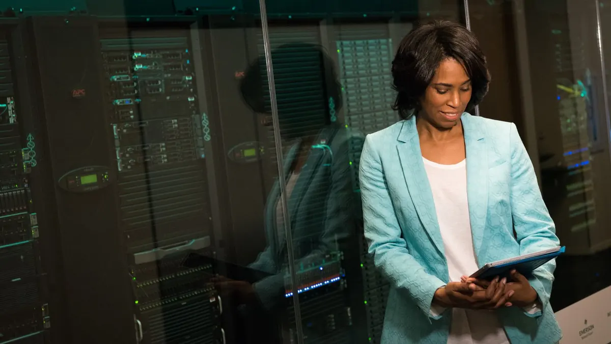 IT professional checking a tablet beside server racks in a data center